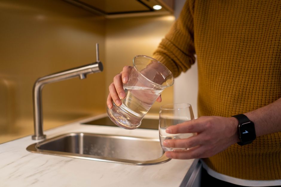 A glass of clear water with the Brooklyn Bridge in the background, addressing whether Brooklyn tap water is safe to drink in 2026 and its quality.